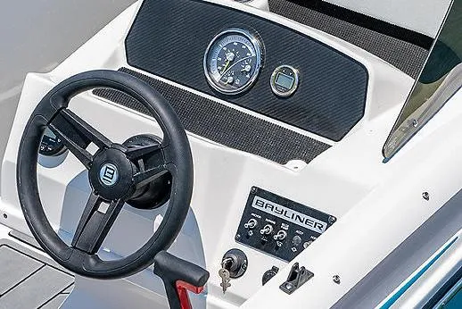 Slide: The Image of 2024 Bayliner Element M17 boat interior with seating and steering console, parked on a concrete surface. - 8