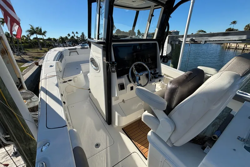 Slide: The Image of 2023 World Cat 295 CC boat interior with helm, seating, and waterfront view. - 13