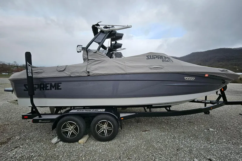 Slide: The Image of 2022 Supreme S220 boat on trailer with protective cover, parked outdoors. - 1