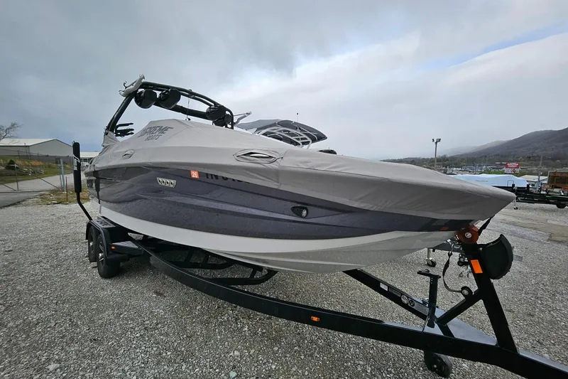 Slide: The Image of 2022 Supreme S220 boat on trailer, covered, parked outdoors under cloudy sky. - 2