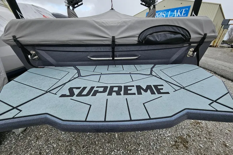 Slide: The Image of 2022 Supreme S220 boat with custom deck design, parked outdoors. - 3