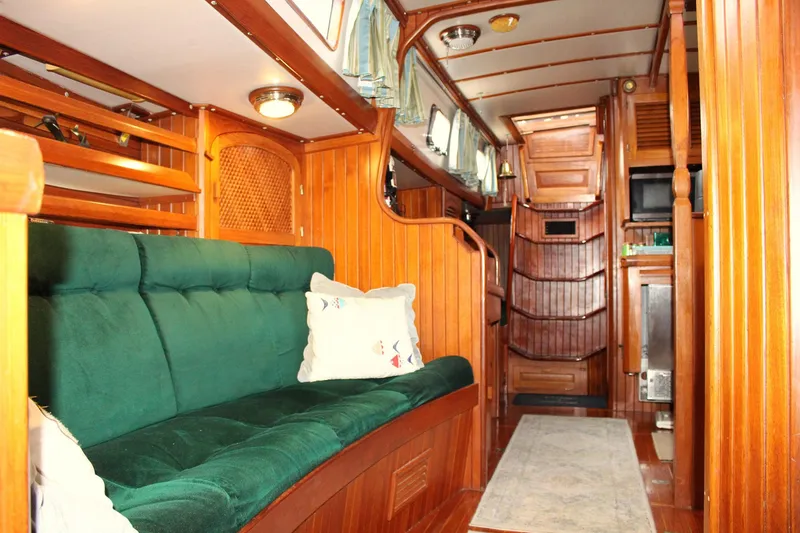 Slide: The Image of Cozy interior of 1990 Slocum 43 sailboat with green sofa and wooden paneling. - 12