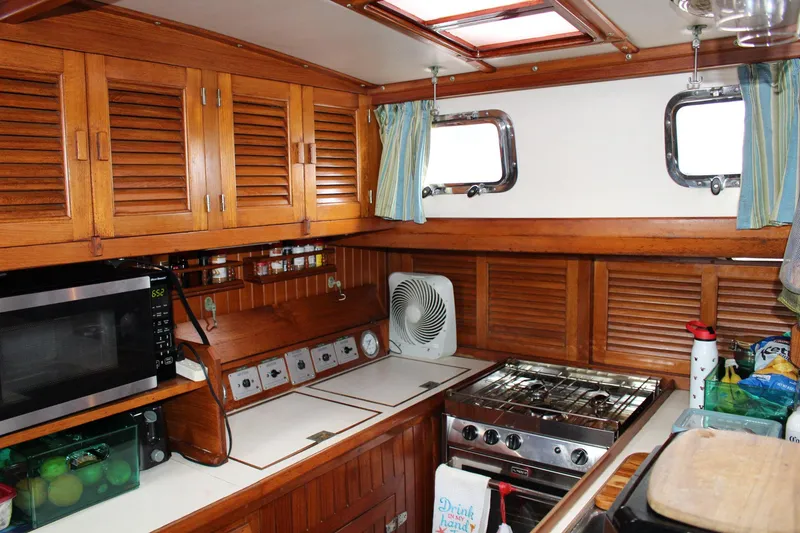 Slide: The Image of Cozy 1990 Slocum 43 yacht kitchen with wooden cabinets, stove, and microwave. - 17