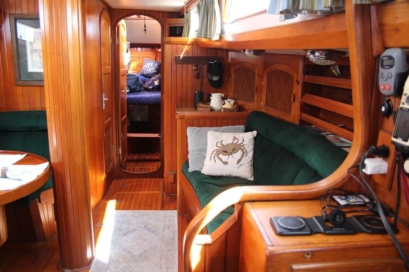 Slide: The Image of Cozy interior of a 1990 Slocum 43 sailboat with wooden paneling and green seating. - 18