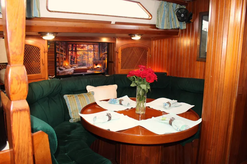 Slide: The Image of Cozy 1990 Slocum 43 yacht interior with dining area, wooden paneling, and floral centerpiece. - 19