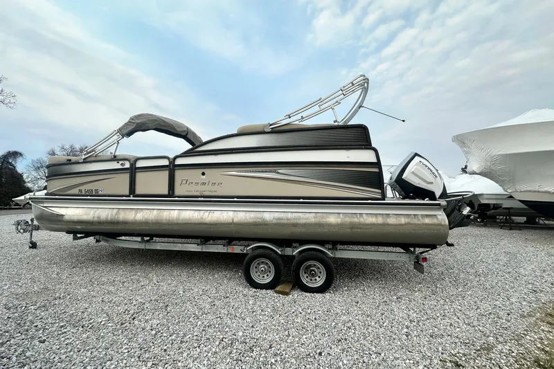 The Image of 2016 Premier 260 Grand View pontoon boat on trailer, parked on gravel lot. - 0