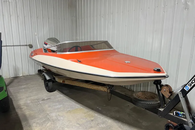 The Image of 1971 Glastron/Carlson GT 15 boat with orange and white design on a trailer. - 0