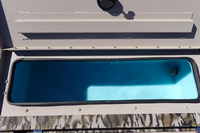 Slide: The Image of Open storage compartment in 2026 Avid 18 Commander boat, featuring a blue interior. - 22