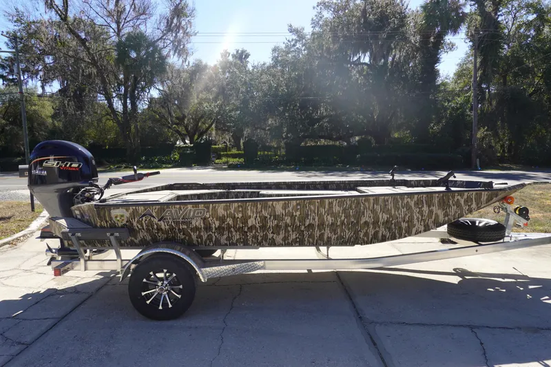 Slide: The Image of 2026 Avid 18 Commander boat with camouflage design on a trailer, parked outdoors. - 4