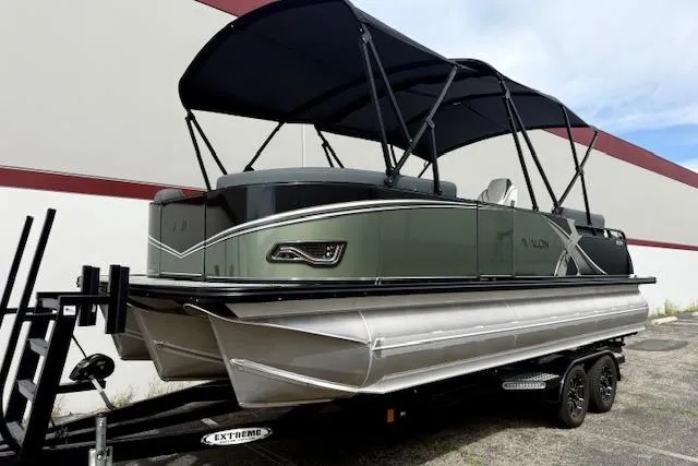 Slide: The Image of 2026 Avalon LSZ Quad Lounge Shift pontoon boat on trailer, featuring sleek design and canopy. - 22