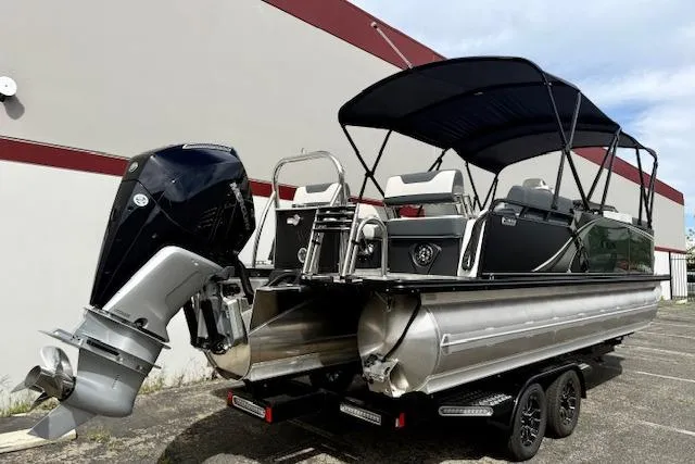 Slide: The Image of 2026 Avalon LSZ Quad Lounge Shift pontoon boat with outboard motor, parked outdoors. - 33