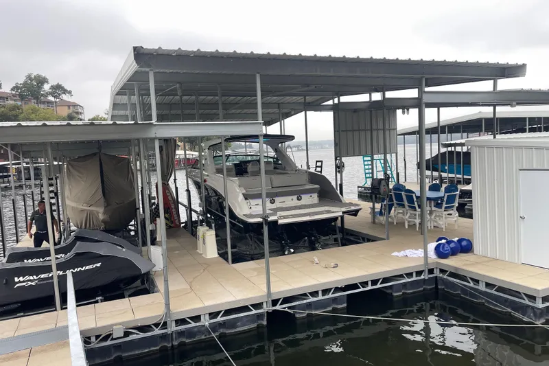 Slide: The Image of 2023 Sea Ray SLX 400 docked under a covered marina with WaveRunner nearby. - 16