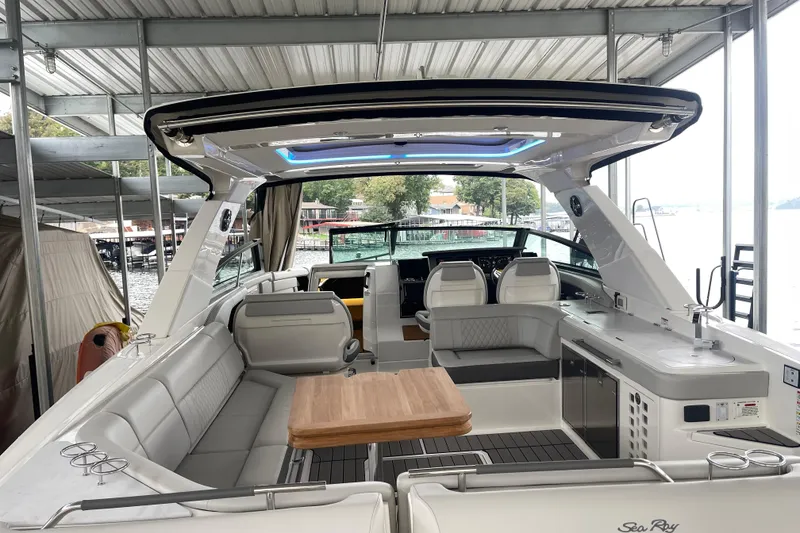 Slide: The Image of 2023 Sea Ray SLX 400 luxury boat interior with seating and table under a covered dock. - 24