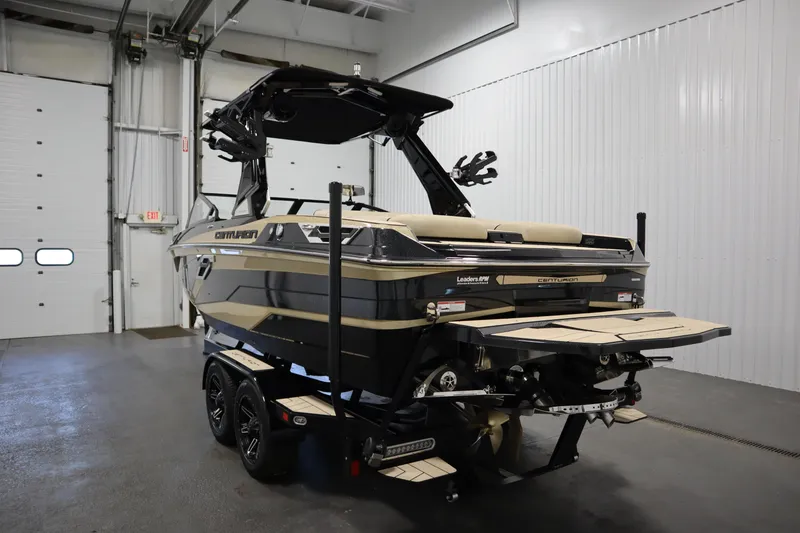 Slide: The Image of 2024 Centurion Ri230 boat in showroom, black and gold design, on trailer. - 7