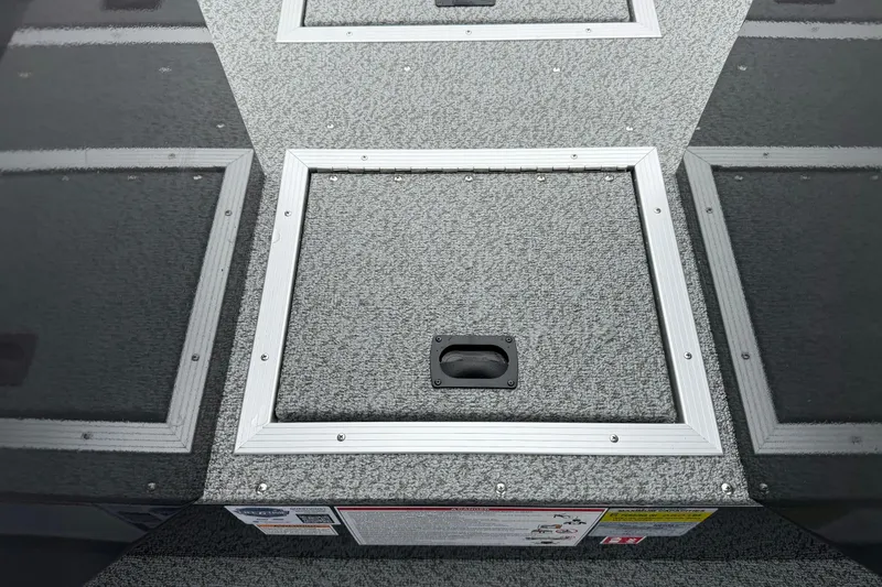 Slide: The Image of 2026 Smoker Craft Osprey 172 boat storage compartment with textured gray surface and metal trim. - 18