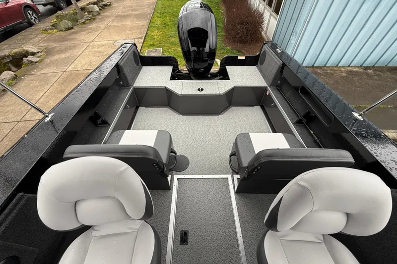 Slide: The Image of 2026 Smoker Craft Osprey 172 boat interior with seating and motor, parked outdoors. - 8