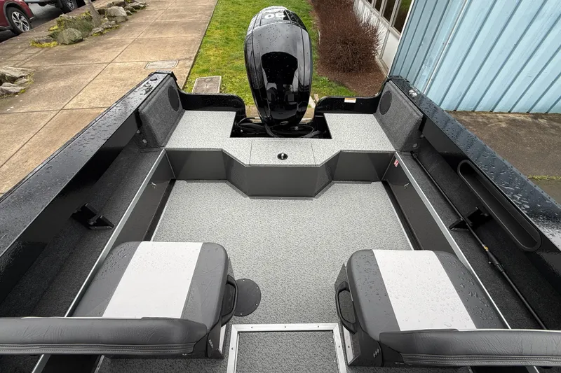 Slide: The Image of 2026 Smoker Craft Osprey 172 boat interior with seating and motor, parked outdoors. - 9