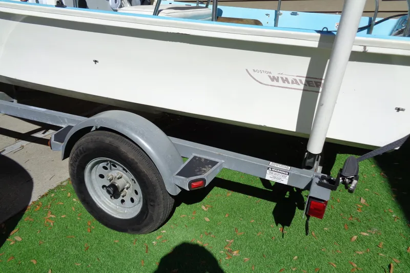 Slide: The Image of 1970 Boston Whaler 17 Montauk boat on trailer, parked on artificial grass. - 13