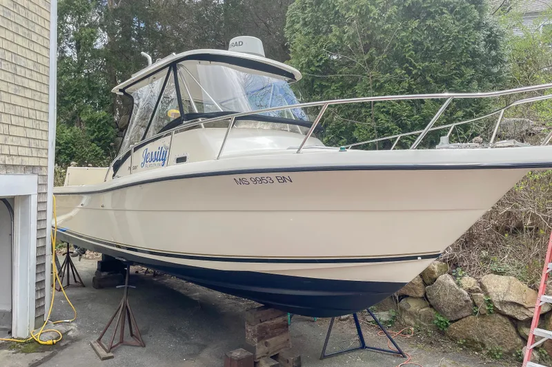 Slide: The Image of 1997 Pursuit 2870 Walkaround boat on stands, parked beside a house. - 2