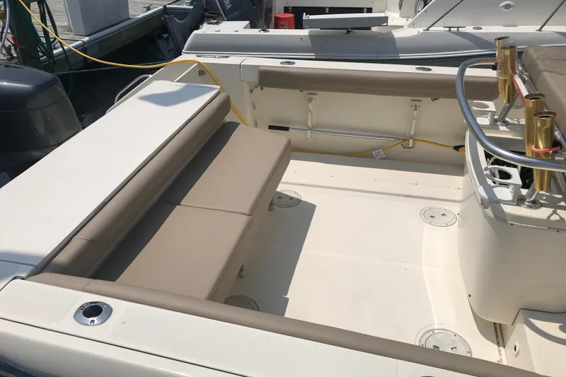 Slide: The Image of 1997 Pursuit 2870 Walkaround boat interior with cushioned seating and rod holders. - 3