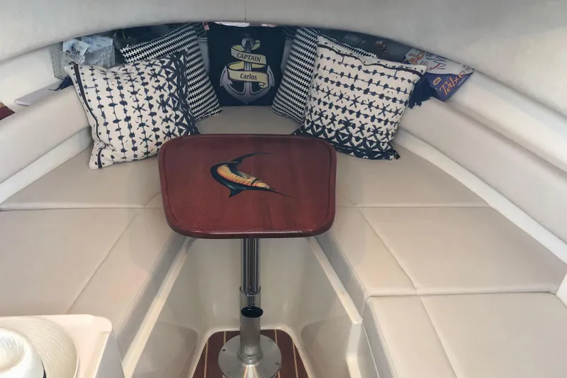 Slide: The Image of 1997 Pursuit 2870 Walkaround cabin with decorative pillows and wooden table. - 6