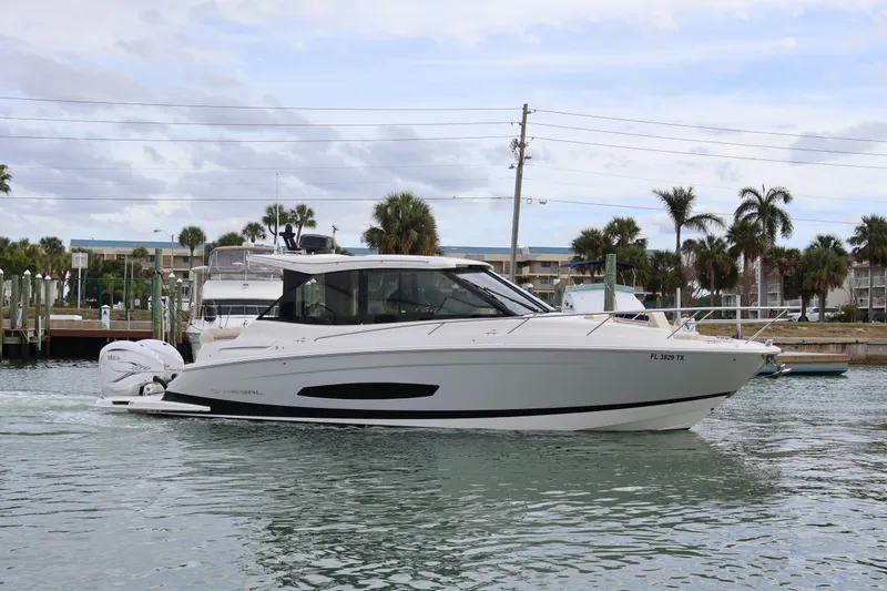 Slide: The Image of 2022 Regal 36 XO boat cruising in a marina with palm trees in the background. - 2