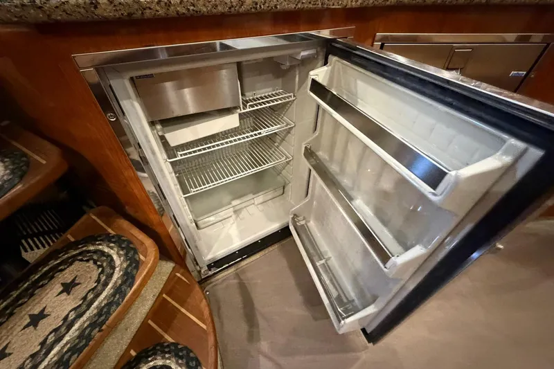 Slide: The Image of Open refrigerator inside 2005 Sea Ray 390 Sundancer yacht, showcasing interior shelves and storage. - 15
