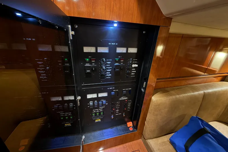 Slide: The Image of Electrical panel inside 2005 Sea Ray 390 Sundancer yacht cabin, featuring wood paneling and seating. - 22