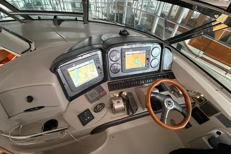 Slide: The Image of 2005 Sea Ray 390 Sundancer helm with navigation screens and wooden steering wheel. - 8