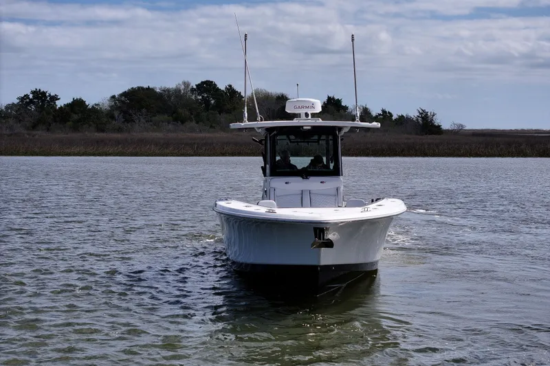 Slide: The Image of 2023 Crevalle 33 CSF boat navigating calm waters under a cloudy sky. - 2
