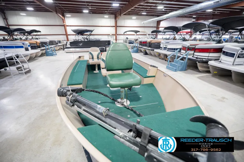 Slide: The Image of 1999 Lund 1650 Explorer SS boat in showroom, surrounded by various pontoon boats. - 12