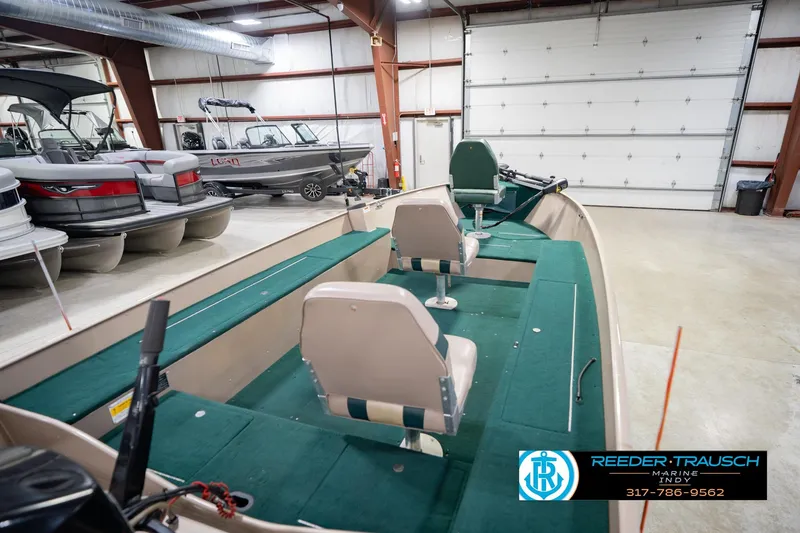 Slide: The Image of 1999 Lund 1650 Explorer SS boat in showroom, featuring green interior and dual seats. - 13