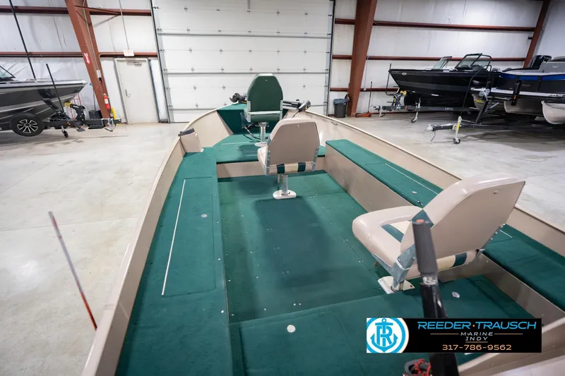 Slide: The Image of 1999 Lund 1650 Explorer SS boat interior with green seating in a showroom. - 14