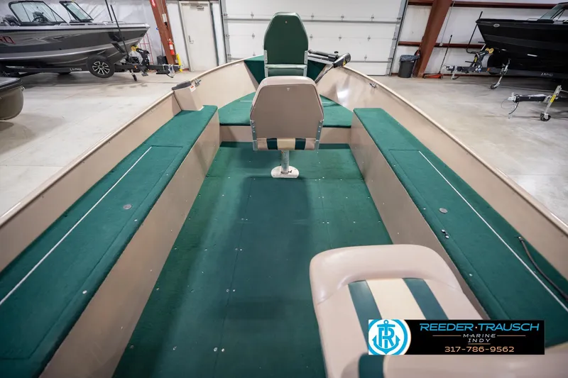 Slide: The Image of 1999 Lund 1650 Explorer SS boat interior with green seating in a showroom. - 15
