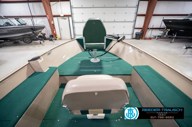 Slide: The Image of 1999 Lund 1650 Explorer SS boat interior with green seating, displayed in a showroom. - 16