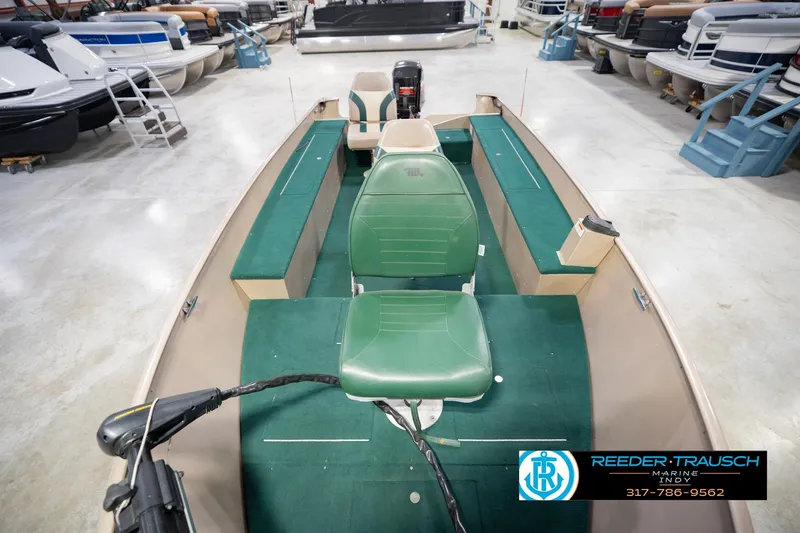 Slide: The Image of 1999 Lund 1650 Explorer SS boat interior with green seating, displayed in a showroom. - 18