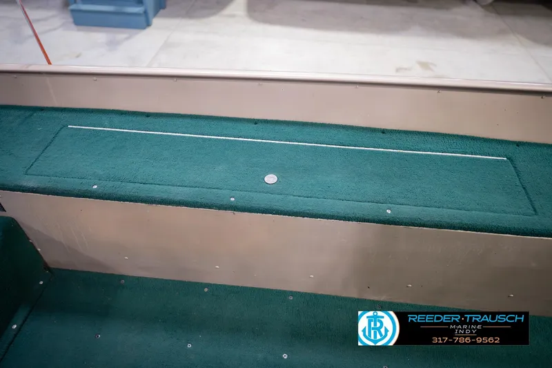 Slide: The Image of 1999 Lund 1650 Explorer SS boat interior with green carpet and storage compartment. - 23