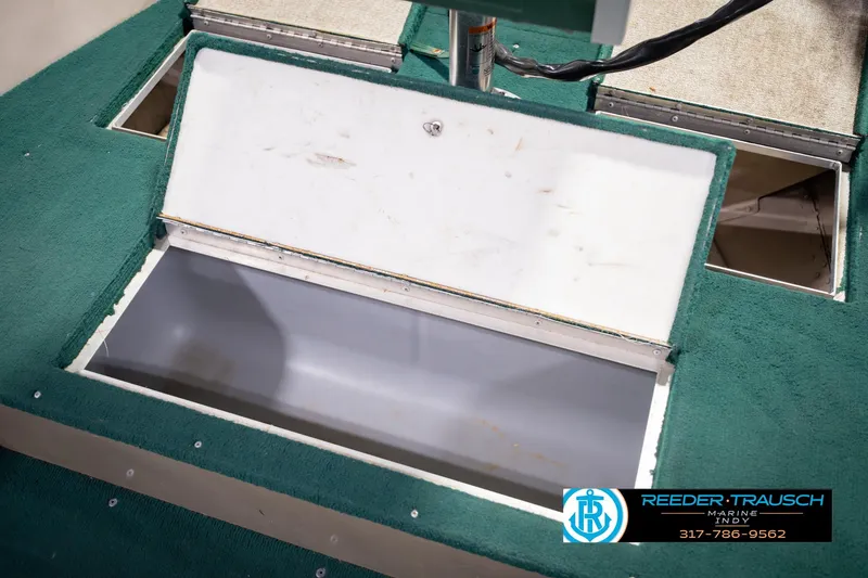 Slide: The Image of 1999 Lund 1650 Explorer SS boat storage compartment with green carpet and open hatch. - 26