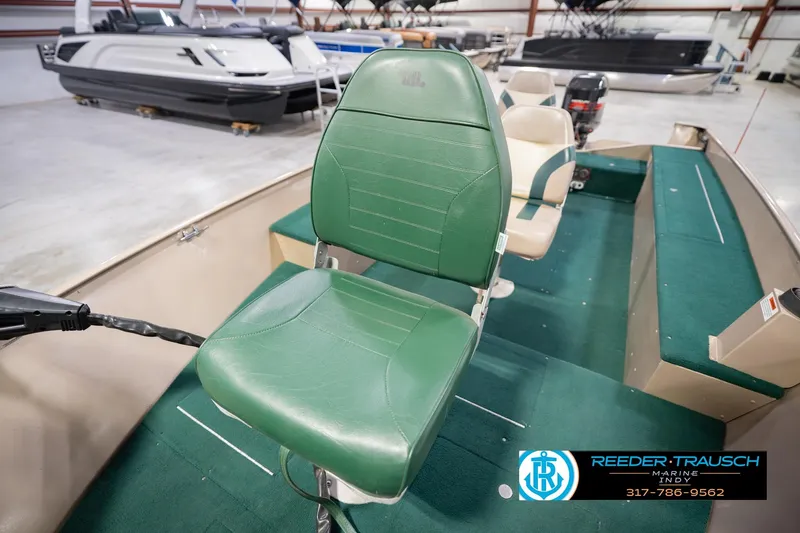 Slide: The Image of 1999 Lund 1650 Explorer SS boat interior with green seating in showroom. - 31