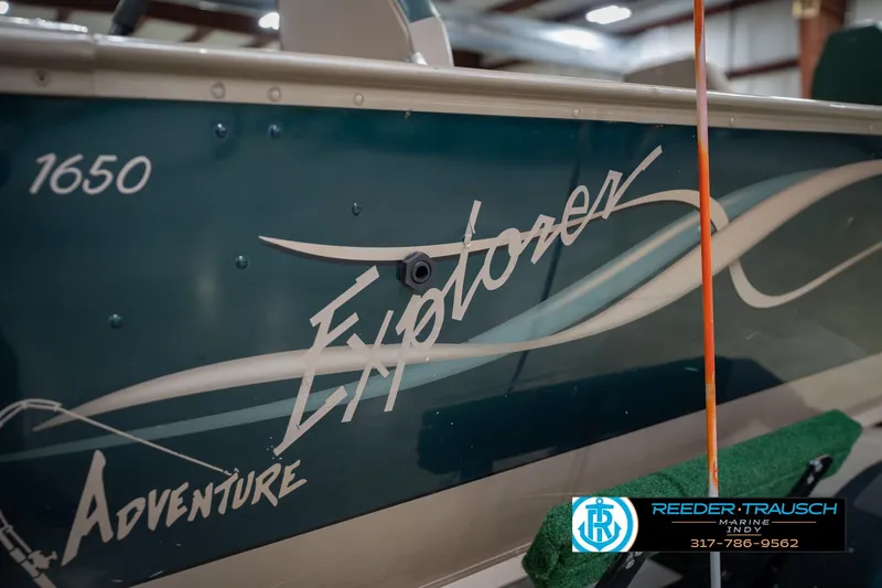 Slide: The Image of 1999 Lund 1650 Explorer SS boat with "Adventure" graphics in a showroom. - 42