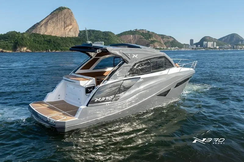 Slide: The Image of 2026 NX Boats NX370 cruising on scenic waters with lush hills in the background. - 2