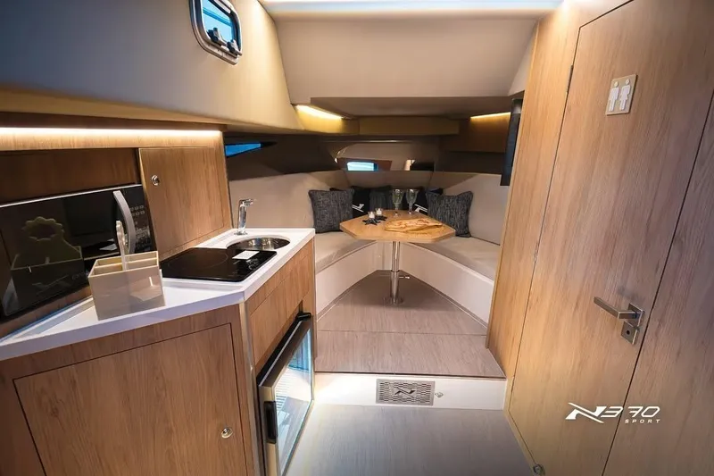Slide: The Image of Interior of 2026 NX Boats NX370, featuring modern kitchenette and cozy seating area. - 8