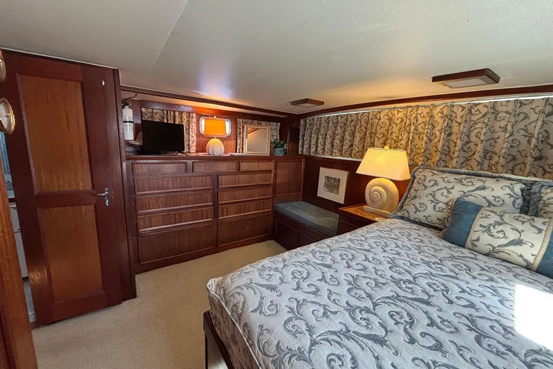 Slide: The Image of Interior of 1979 Hatteras 53 Motor Yacht with elegant wood furnishings and patterned bedding. - 37