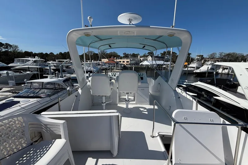Slide: The Image of 1979 Hatteras 53 Motor Yacht at marina, featuring spacious upper deck and helm station. - 45