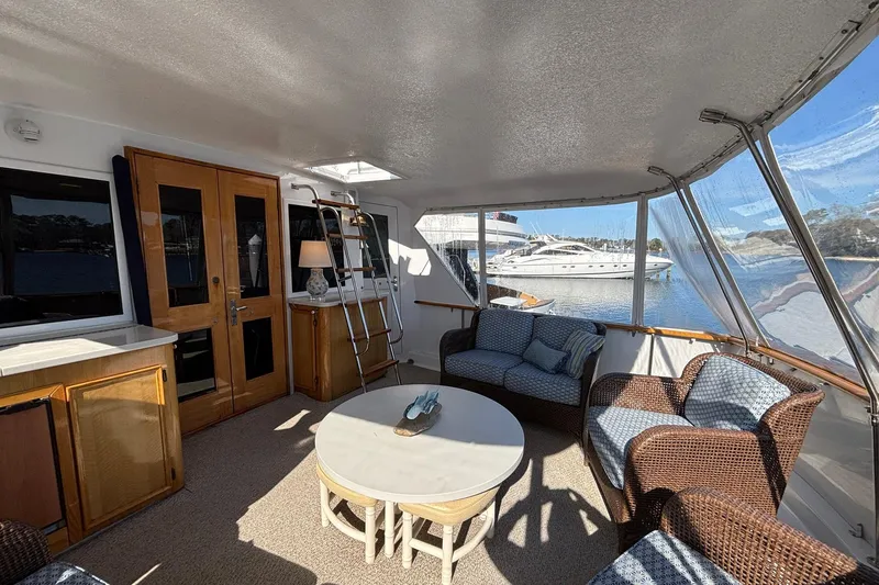 Slide: The Image of 1979 Hatteras 53 Motor Yacht interior with wicker seating and waterfront view. - 6