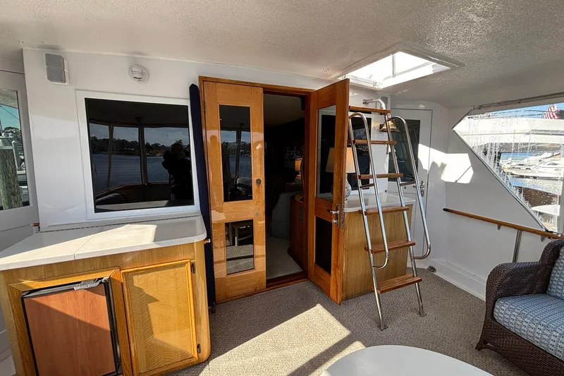 Slide: The Image of 1979 Hatteras 53 Motor Yacht interior with wooden doors, ladder, and waterfront view. - 9