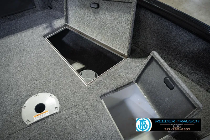 Slide: The Image of 2022 Lund 1875 Impact boat storage compartments with carpeted interior and Reeder-Trausch Marine logo. - 30