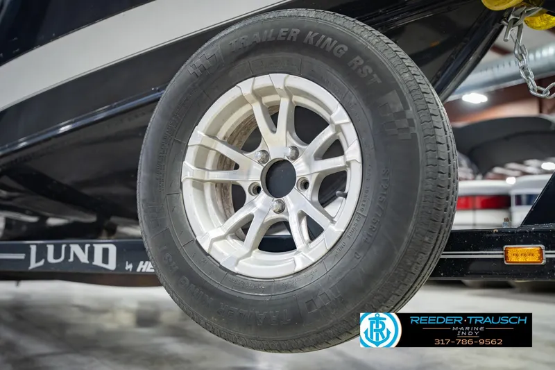 Slide: The Image of 2022 Lund 1875 Impact boat trailer tire in a showroom setting. - 61