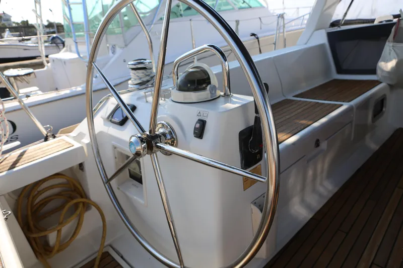 Slide: The Image of Steering wheel of a 2014 Beneteau Oceanis 41 sailboat, featuring teak deck and navigation equipment. - 8