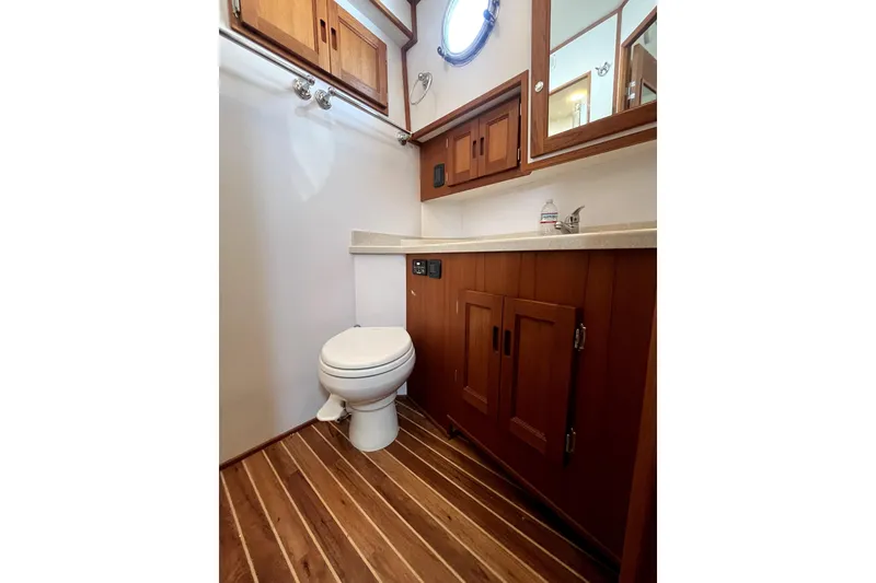 Slide: The Image of 2008 Nordic Tug 42 bathroom with wooden cabinets, porthole, and striped flooring. - 39